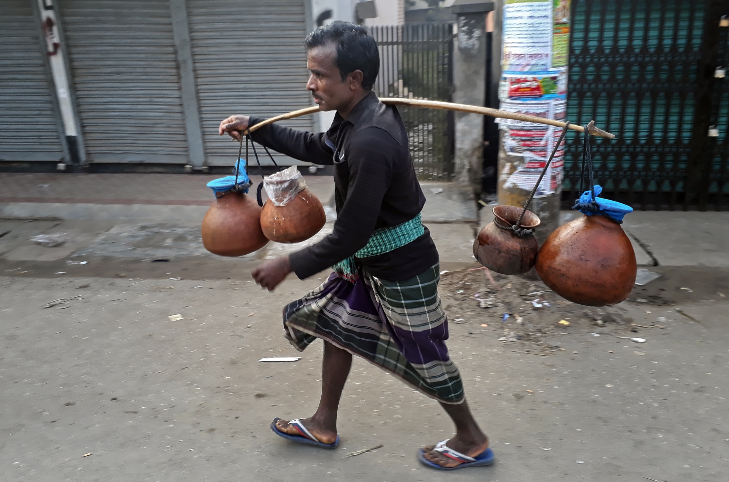 A gachhi walks the streets of Rangpur City carrying pots filled with sap collected from date palm trees, a delicacy in this part of Bangladesh. Photograph by A.M. Ahad