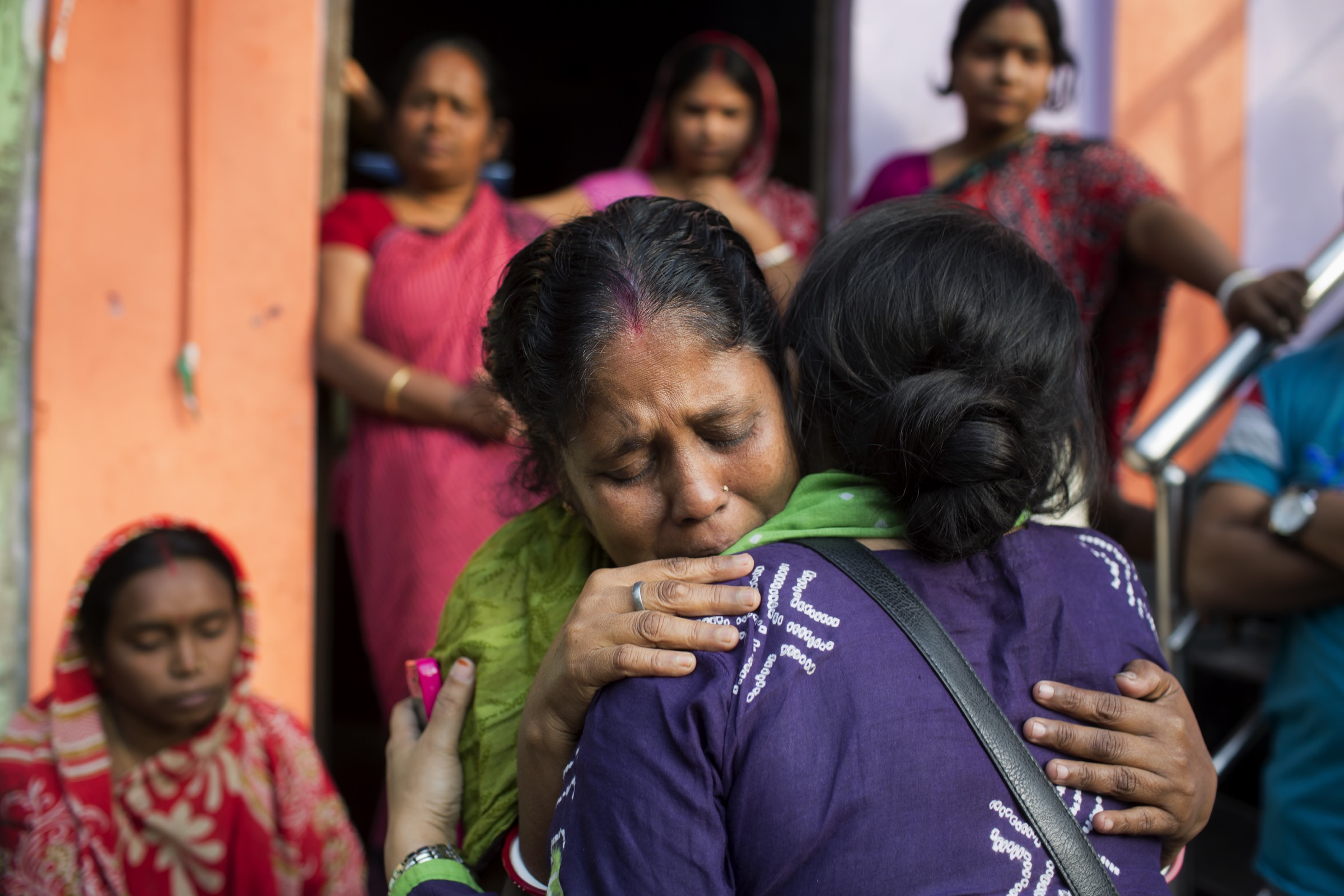 Arifa Nazneen (in purple), a senior medical officer at ICDDR,B is frequently on the front lines of Nipah investigations. Here she tries to comfort a mother in Faridpur whose son who fell ill after drinking date palm sap during a gathering to celebrate his graduation from high school. He has since died. Photograph by A.M. Ahad