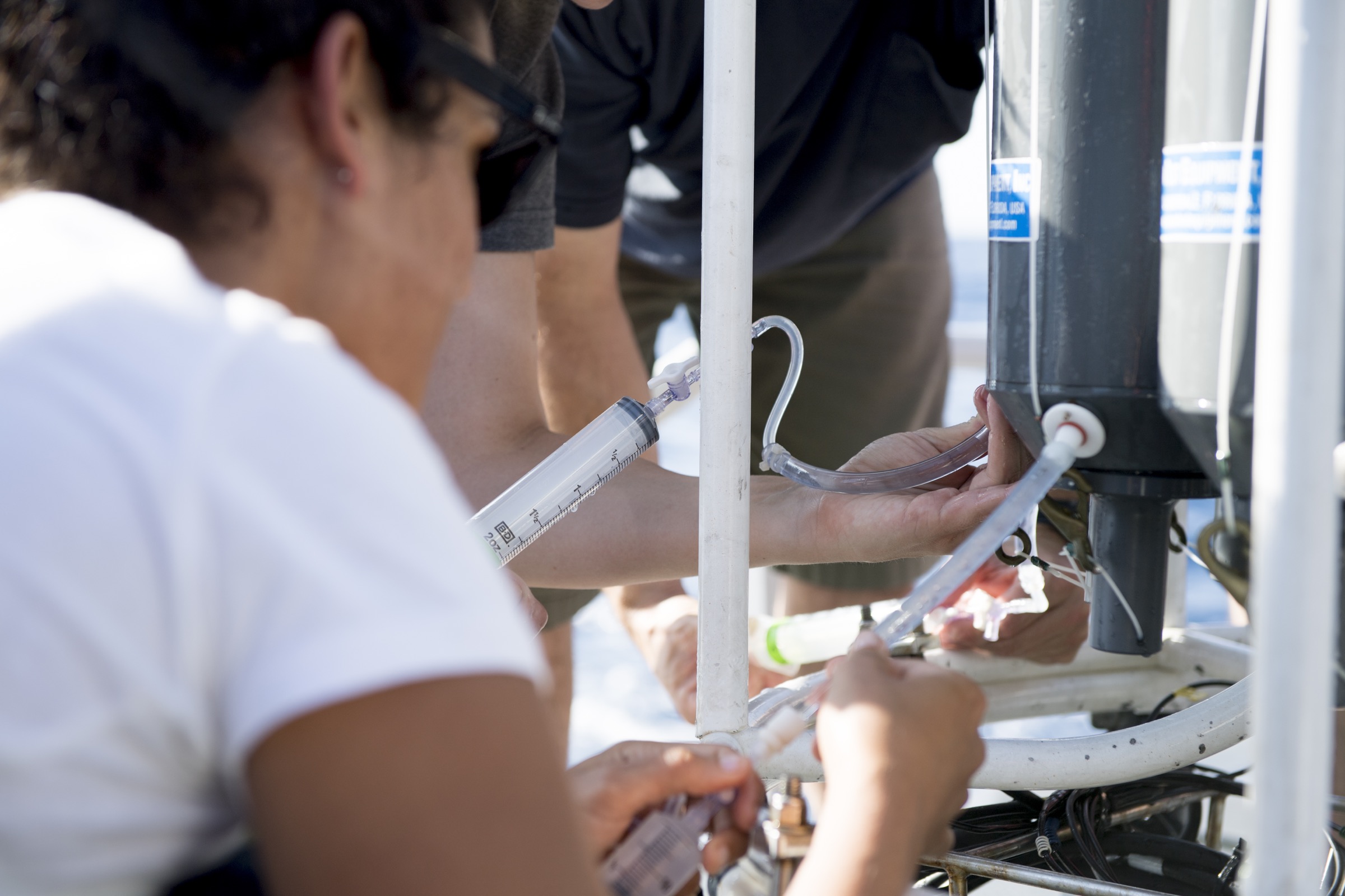 Scientists pull ocean water from the large CTD sampler into smaller syringes in preparation for analysis of the make-up of water deep below the surface. Photograph by Novus Select