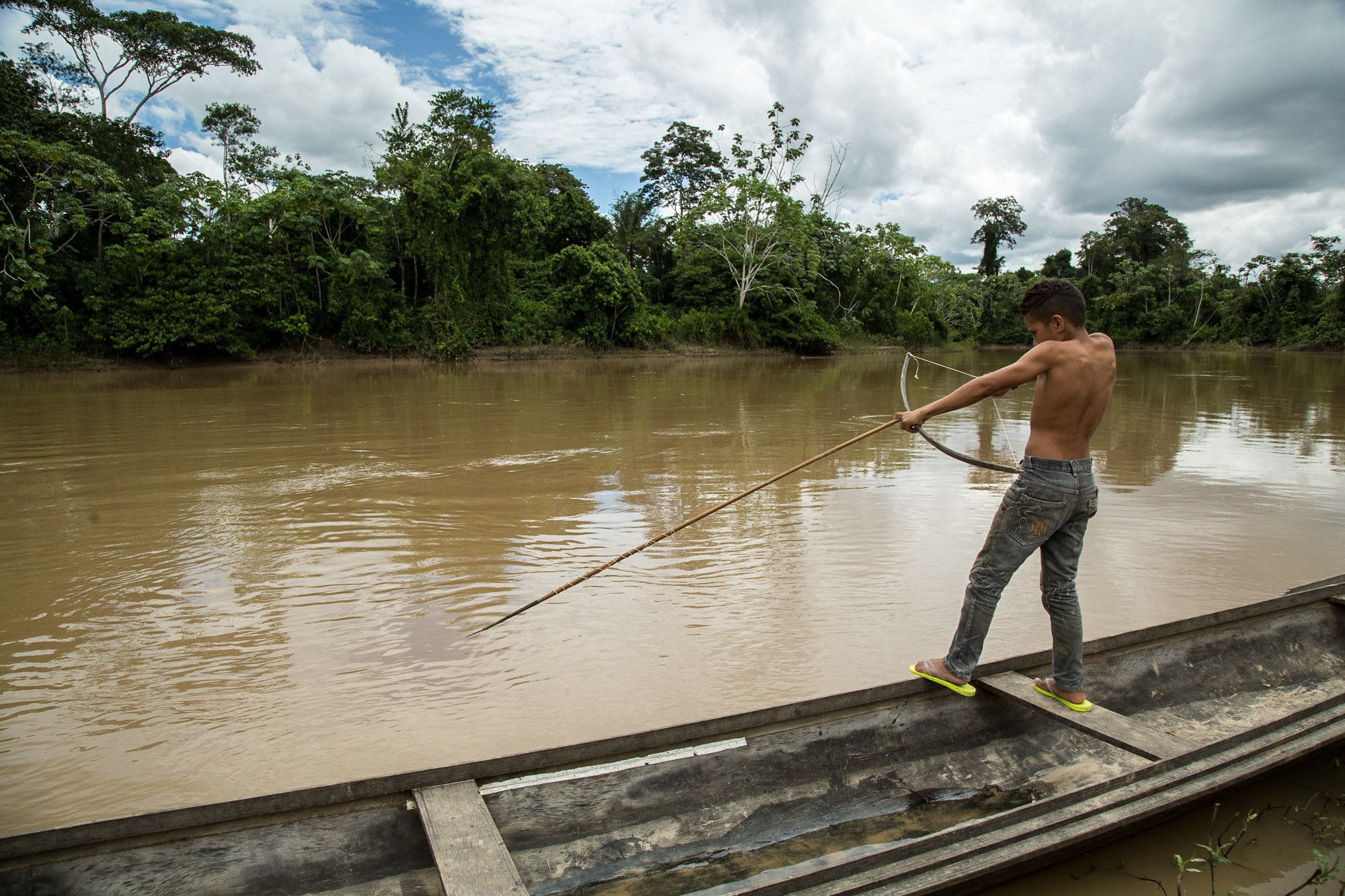 A young boy scans the water in search of his next target. A bow and long arrow is the traditional weapon riberinhos use to catch the monster pirarucu (Arapaima gigas), a fish native to Amazon rivers. Local children learn to fish, hunt and navigate flooded forests in dugout canoes almost as soon as they can walk.