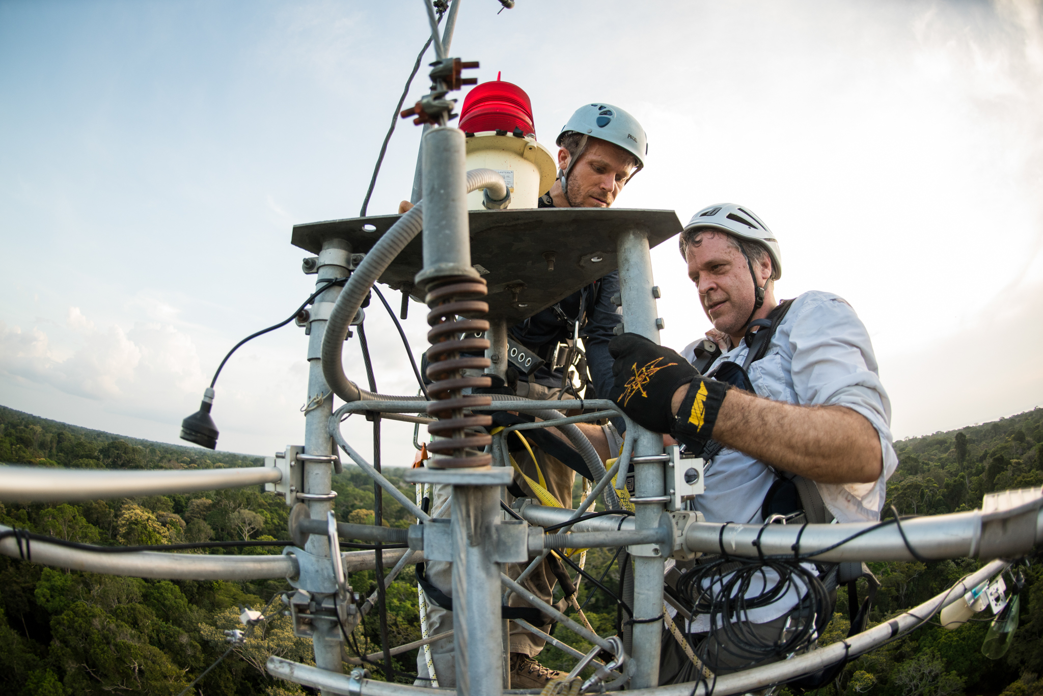 Scott Saleska and Neill Prohaska work at the top of a 220-foot-tall flux tower high above the rainforest canopy.