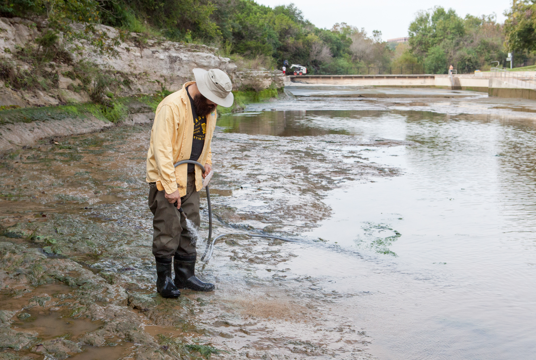 Bendik sprays down freshly exposed limestone at Barton Springs Pool during one of the quarterly cleanings, when the pool’s water level is reduced so volunteers can scrub away slippery algae. Bendik is checking for salamanders that might have been stranded by the receding waters; the hose helps to wash off any mud that might be hiding a small salamander.