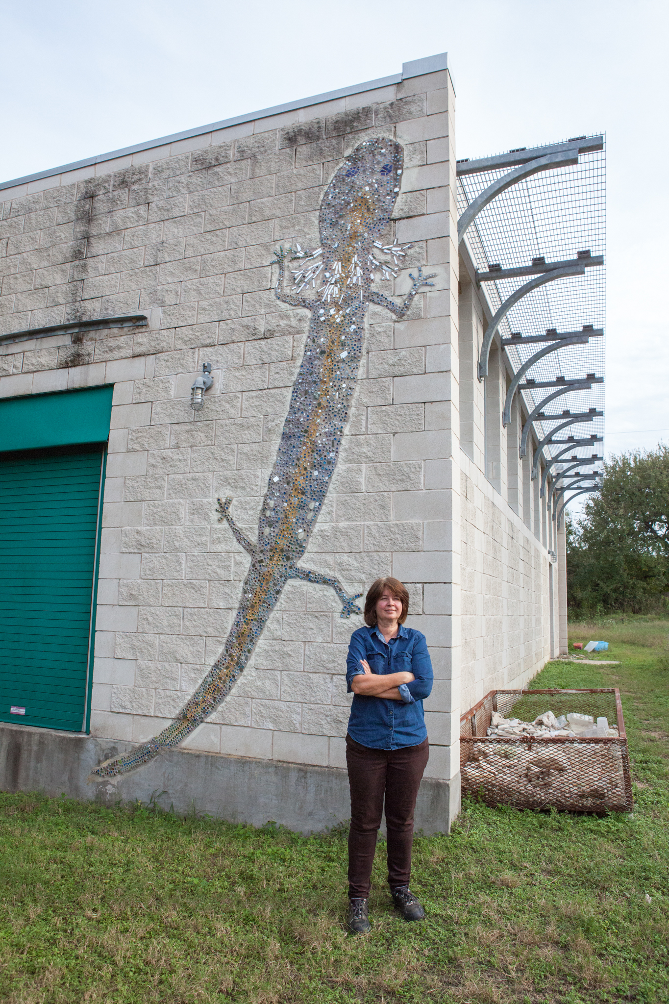 Dee Ann Chamberlain stands in front of the captive breeding facility building, well marked with a salamander mosaic. The breeding facility started out as three tanks that Chamberlain shared space with in her cubicle. There are now about 200 tanks housed in a dedicated building.