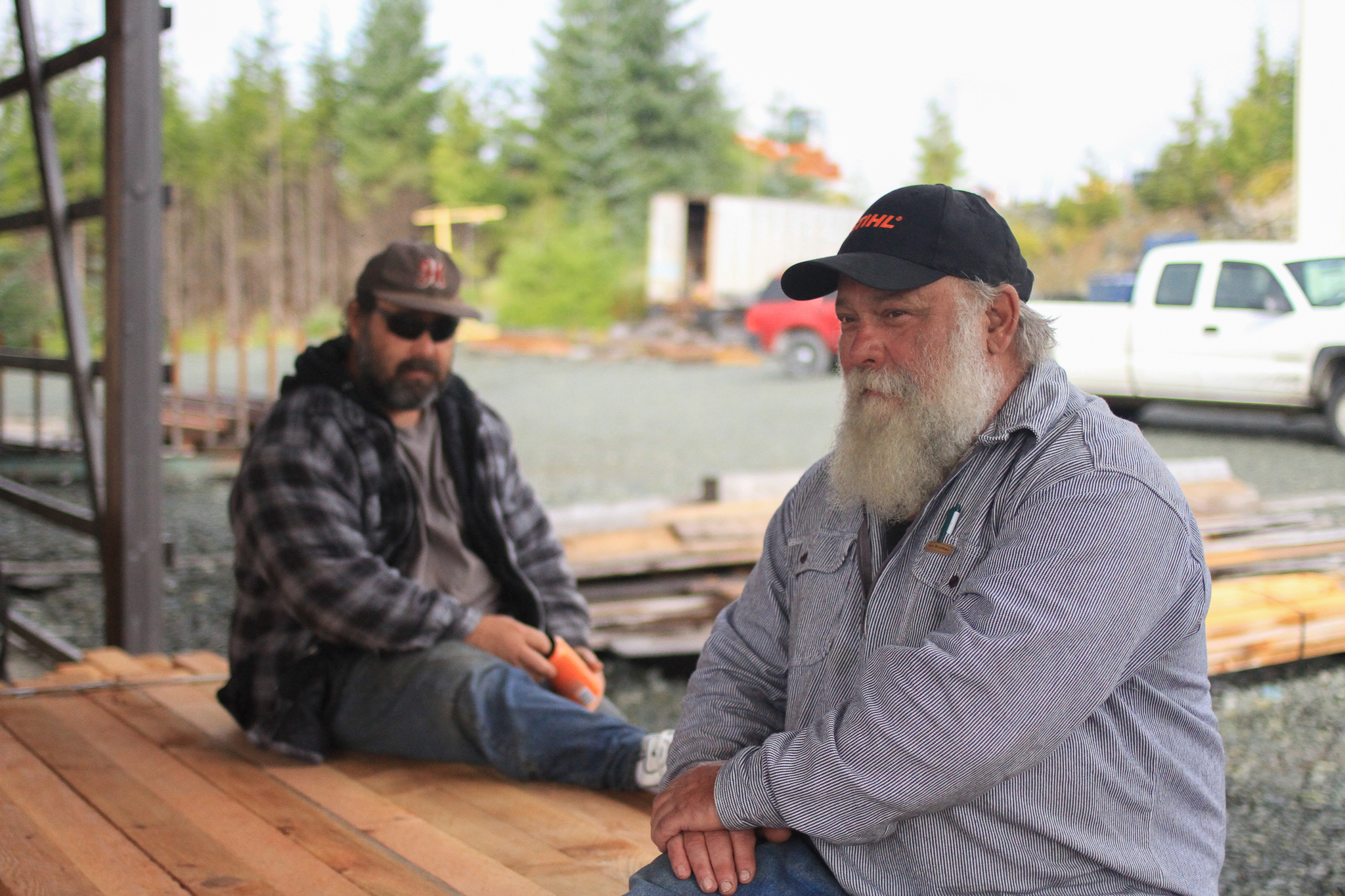 Hans Kohn (right) and his son Josh Kohn talk about young-growth prospects under an open air shelter shielding the mill’s bandsaw and boards from Southeast Alaska’s ever-present rain.