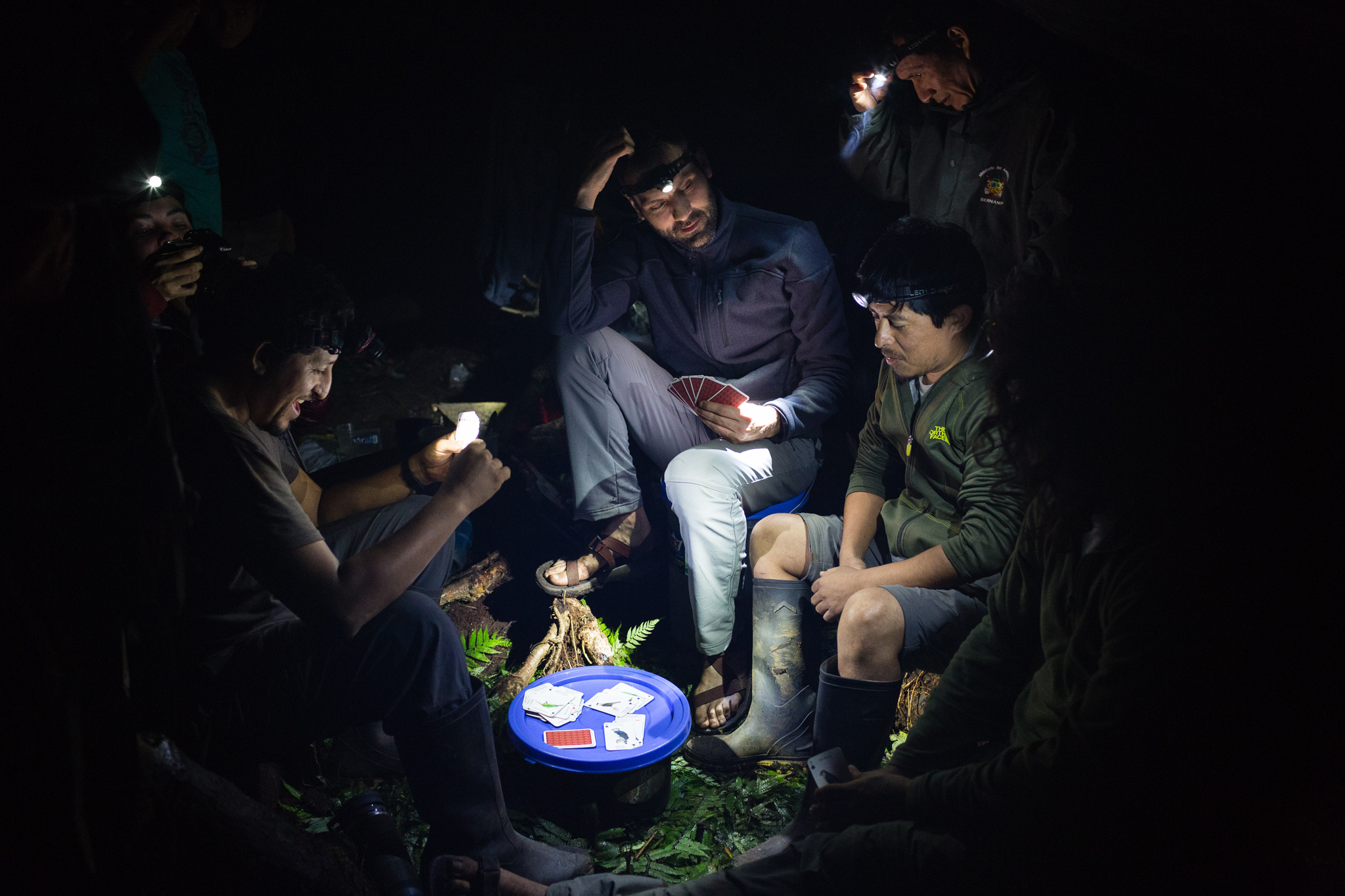 The team members entertain themselves over a game of cards illuminated by headlamp lights. Photo by Andy Isaacson
