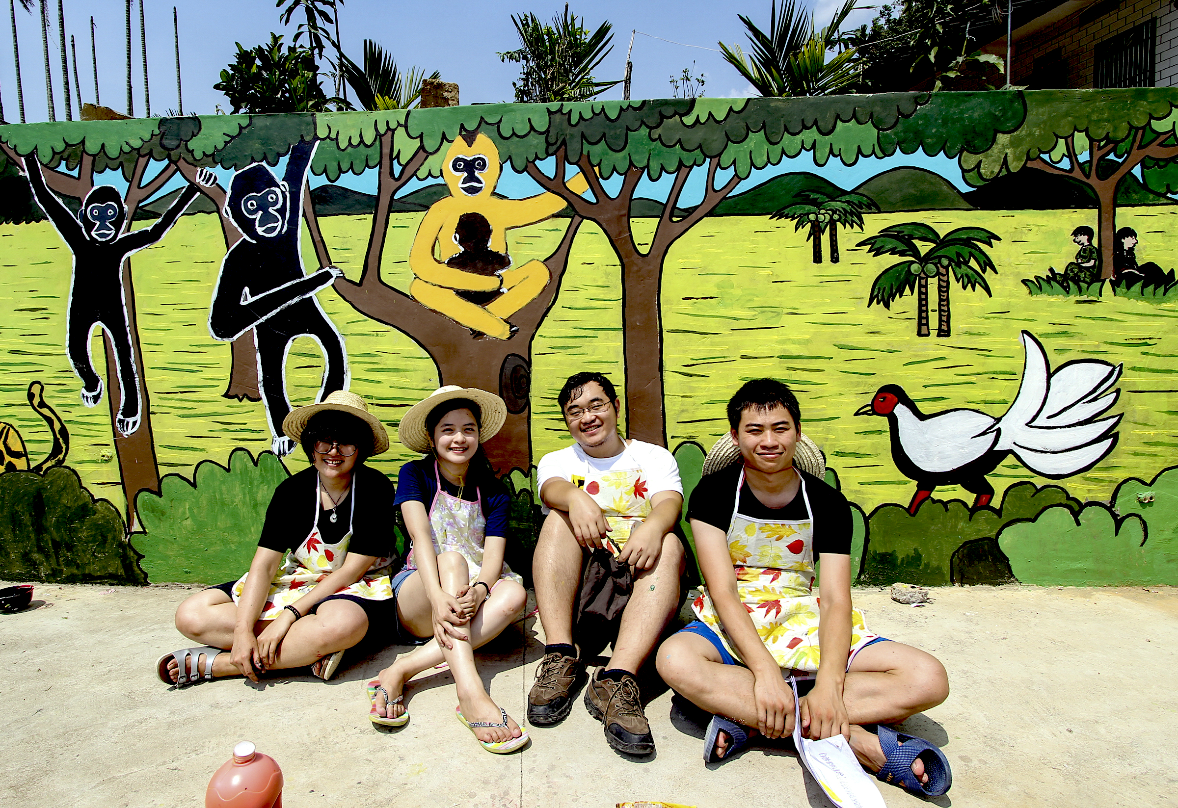 Students sit in front of a new mural of Hainan gibbons in the village of Miao Cun. The mural was painted as part of Kadoorie Farm’s campaign to raise awareness about the Hainan gibbon. Photograph courtesy of Kadoorie Farm & Botanic Garden