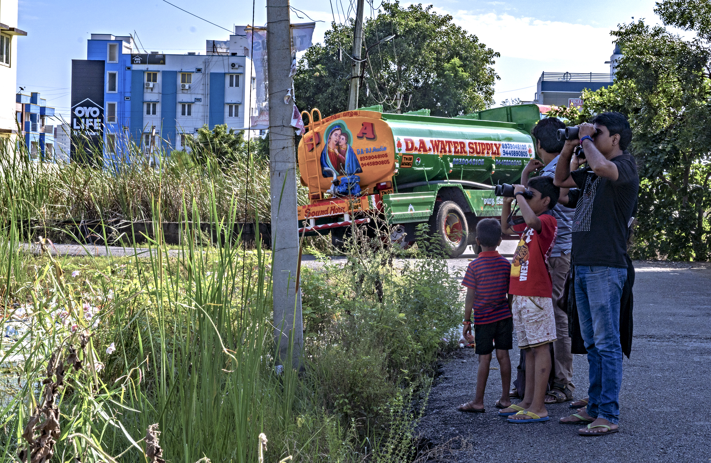 A family watches birds at the edge of Pallikaranai Marsh.