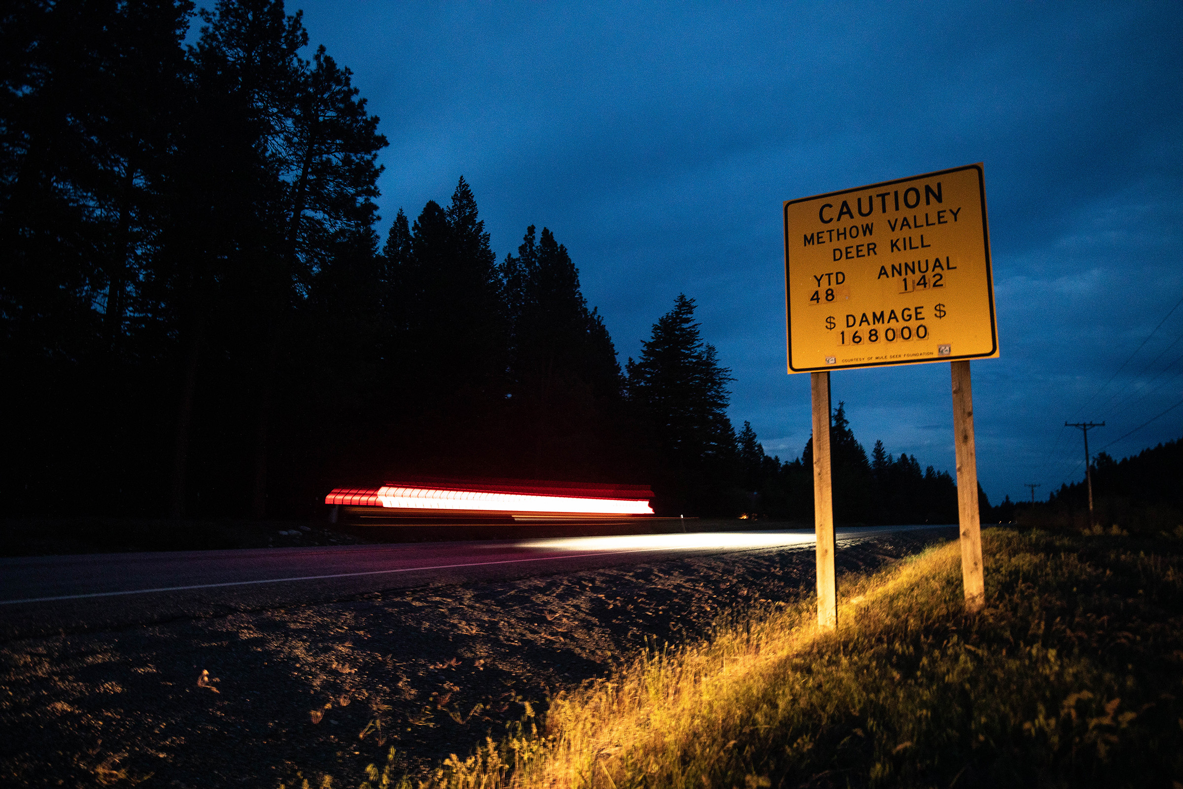 Drivers cruise past a road sign warning of the toll that car strikes can have on both deer and people.