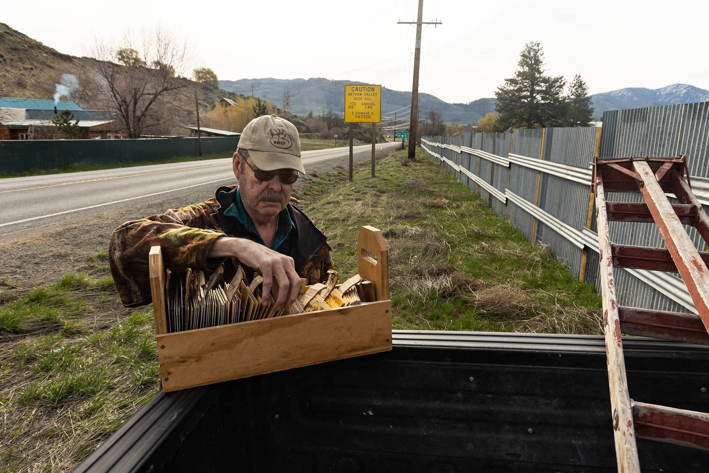 Jim Mountjoy, a volunteer for the Mule Deer Foundation, changes the numbers on a deer strike warning sign located on Highway 20.