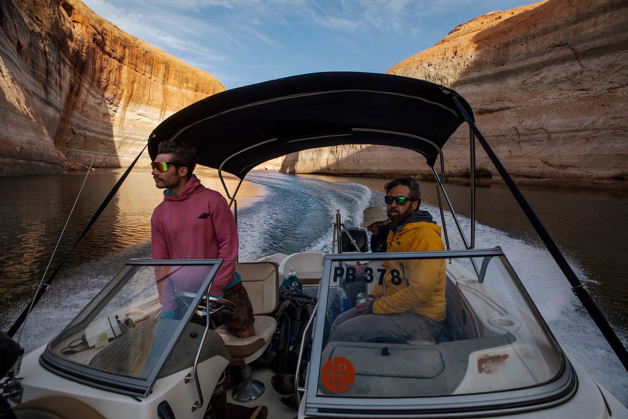 A chilly boat ride into lower Moqui Canyon where research scientist Seth Arens (right) is conducting plant surveys at various sites once flooded by Lake Powell. At the helm is Jack Strauss of the Glen Canyon Institute, and near the stern, botanist Marc Coles-Ritchie, hunkers from the wind.
