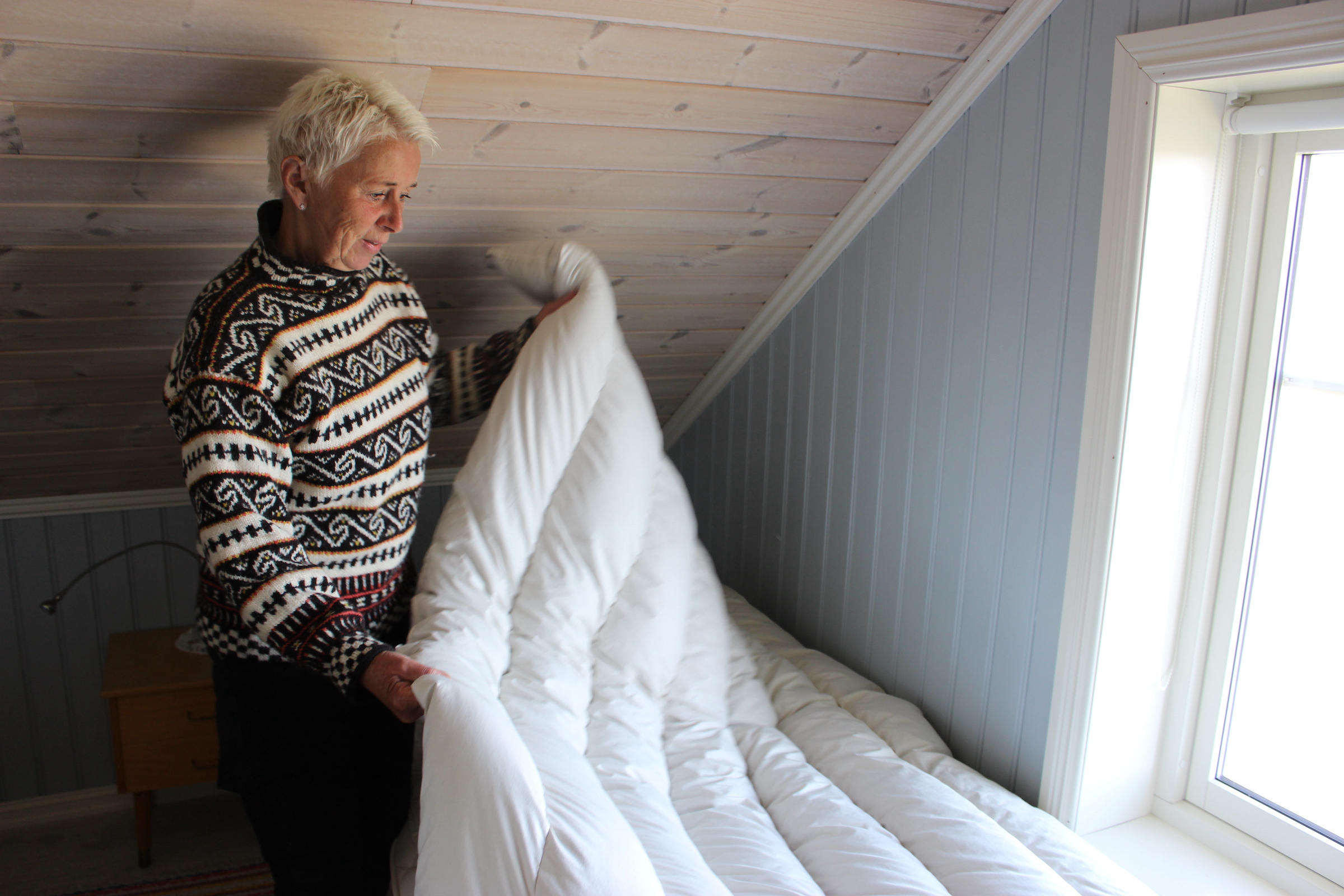 Hildegunn Nordum holds a duvet made by her mother. These blankets stuffed with eiderdown can sell for thousands of dollars and last 50 years or more. Photograph by Devon Fredericksen