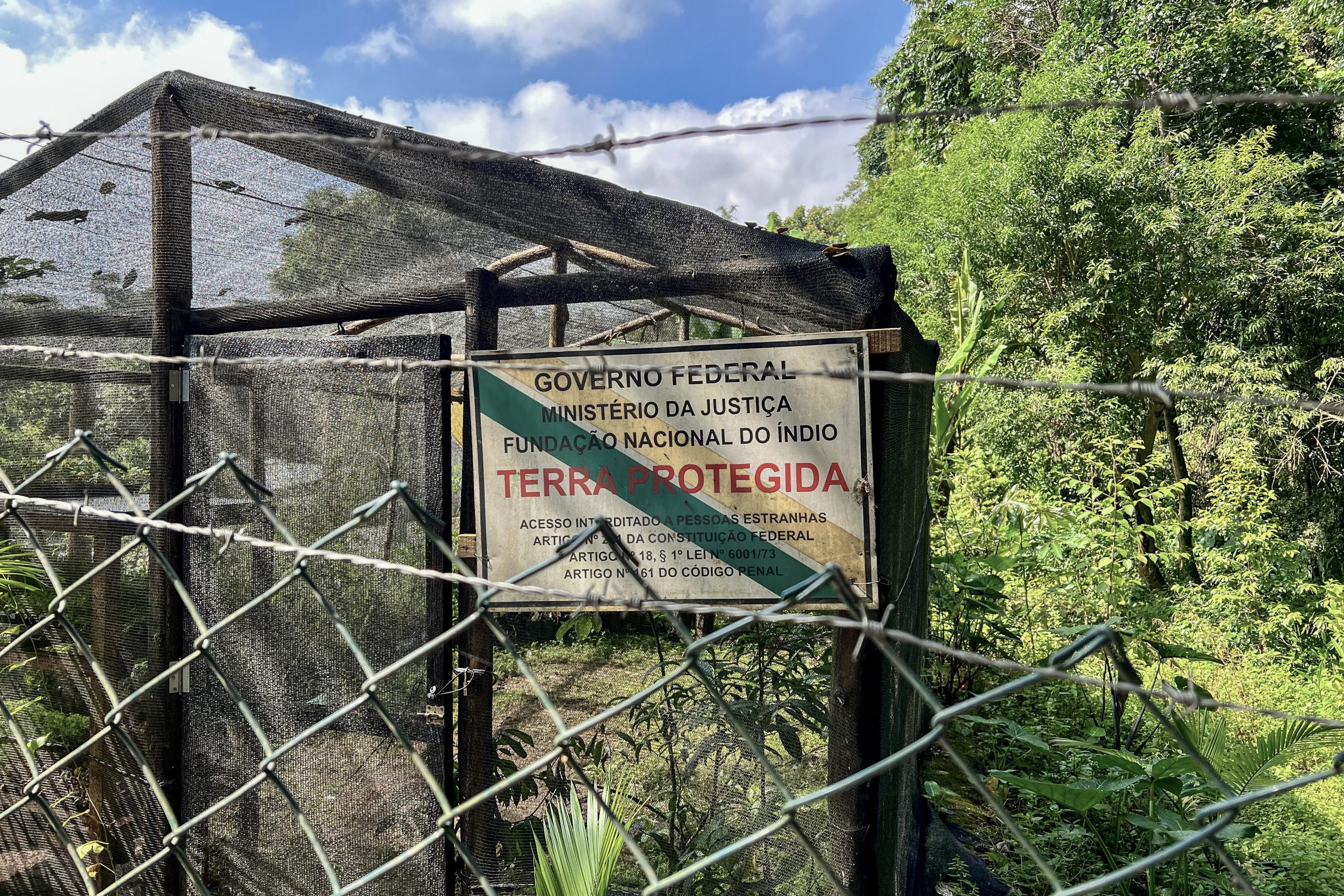 The Guarani from the Jaraguá Indigenous Land grow plant seedlings in a greenhouse for future reforestation projects. A sign on the fence warns against the entry of uninvited visitors on the tribal lands. Photograph by Sofia Moutinho