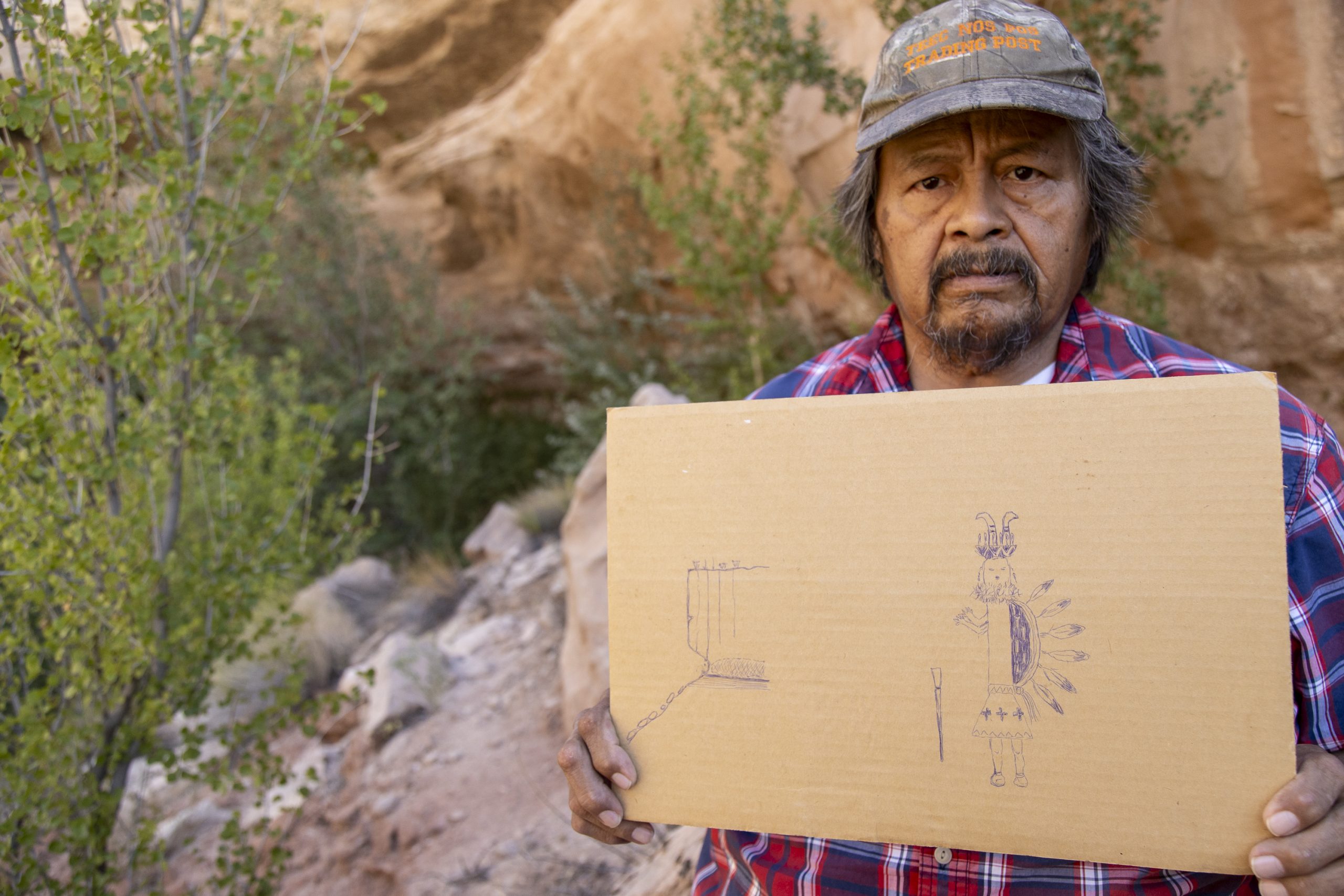 Arnold Clifford displays his drawing of Navajo deities that, in Diné stories and traditions, inhabit the hanging gardens and sandstone bluffs of the Four Corners area.