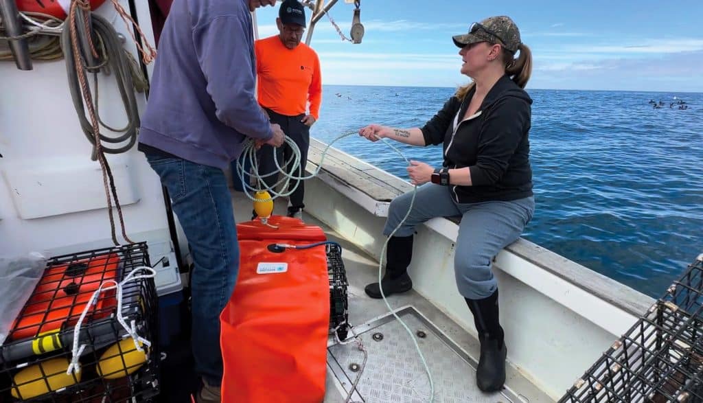 Marine technology researcher Kim Sawicki works with box crab fisher Greg Olson to repack his ropeless gear system off the coast of Santa Barbara, California while scientists Bud Vincent looks on.